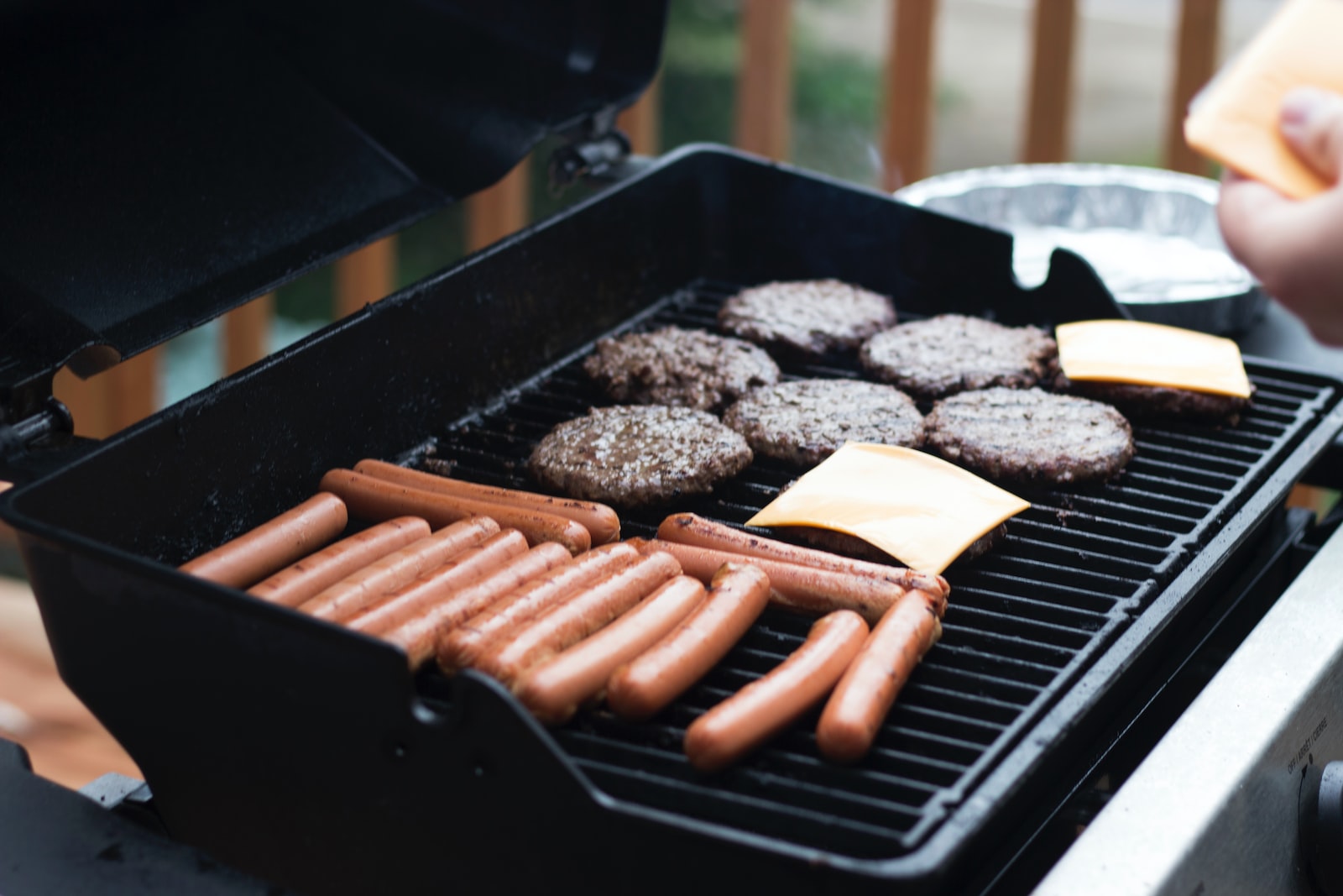 person standing in front grill grilling sausage